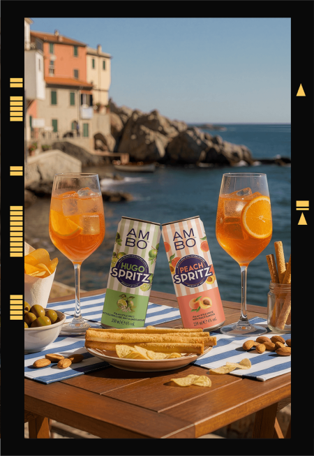 AMBO Hugo Spritz and Orange Spritz served on a seaside table with cocktails and aperitivo snacks.